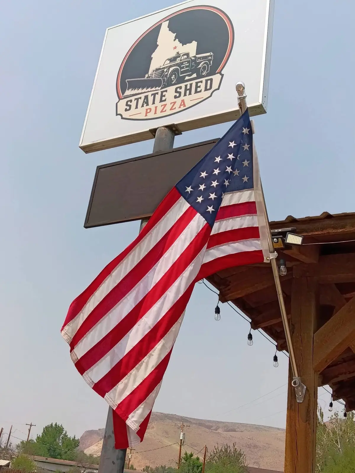 State Shed Pizza sign and American flag outside the restaurant